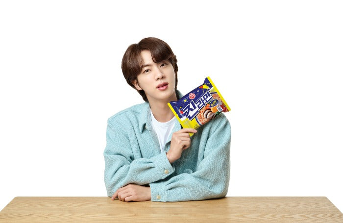 Jin of BTS holds a Jin Ramen packet