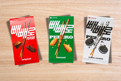Three packages of Lotte Pepero cookies on a wooden surface